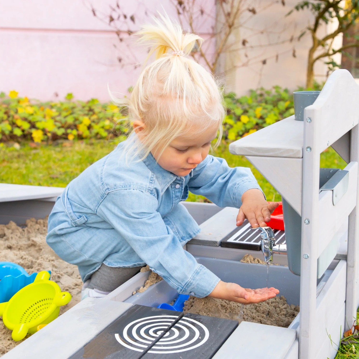 Kind spielt an roba Outdoor Matschküche in Hausoptik aus Holz mit Wasserhahn.