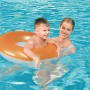 Kind mit Bestway Schwimmring (orange/weiß) im Pool mit Aufsichtsperson.