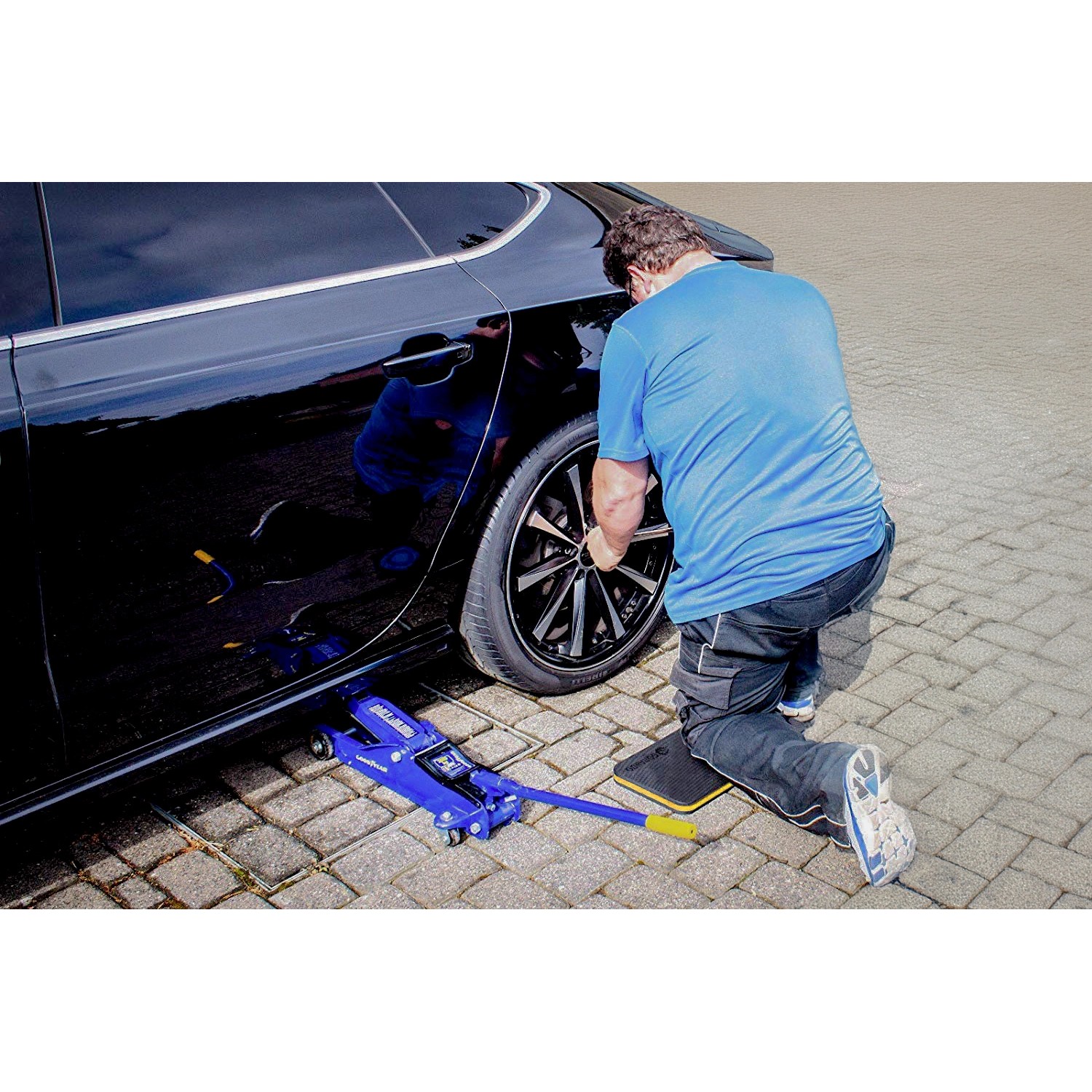 Mann wechselt Reifen am Auto, kniend auf Gorando Premium Kniekissen. Knieschutz für Werkstatt und Garten.