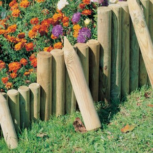 Mini-Palisade aus druckimprägniertem Holz (Ø 8 cm x 50 cm) als Beeteinfassung im Garten.