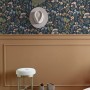 Dunkelblaue Vliestapete mit bunten Feldblumen an einer Wand, kombiniert mit Holzpaneel. Stilvolle Dekoration.