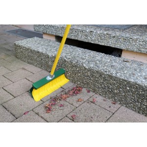 Gelber Krallenbesen (35 cm) mit grünem Kopf und gelbem Stiel im Einsatz auf Pflastersteinen.