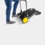 Kärcher S 4 Twin Go!Further Kehrmaschine in Schwarz mit gelben Rädern und Person in Jeans.