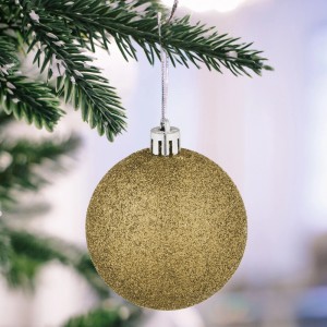 Goldene Glitzer-Weihnachtskugel aus Polystyrol am Tannenbaum mit Bändchen. Festlicher Christbaumschmuck.
