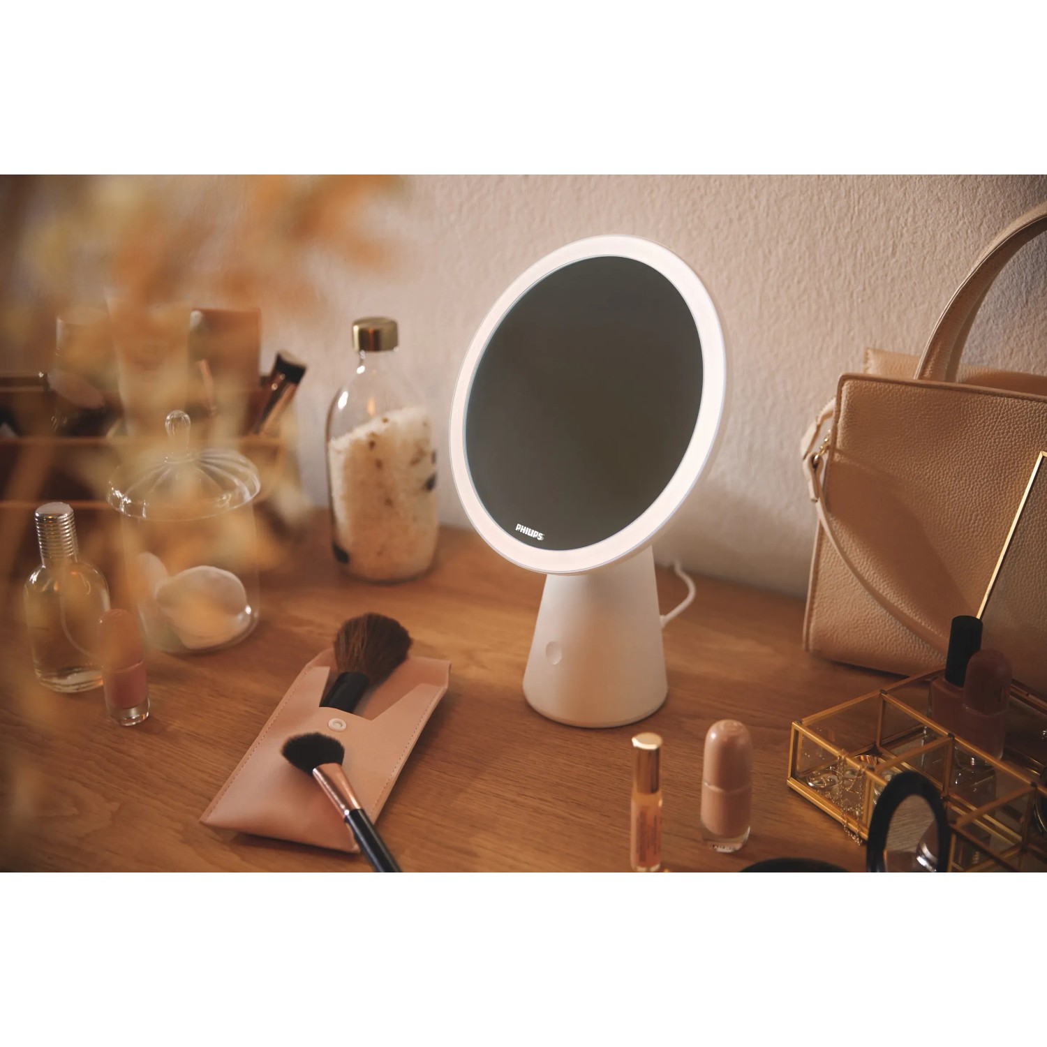 Weiße Philips LED Tischleuchte Mirror mit Spiegel auf einem Tisch mit Kosmetikartikeln.