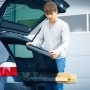 Mann verpackt Holz mit schwarzer LUX Stretchfolie im Kofferraum eines Autos.