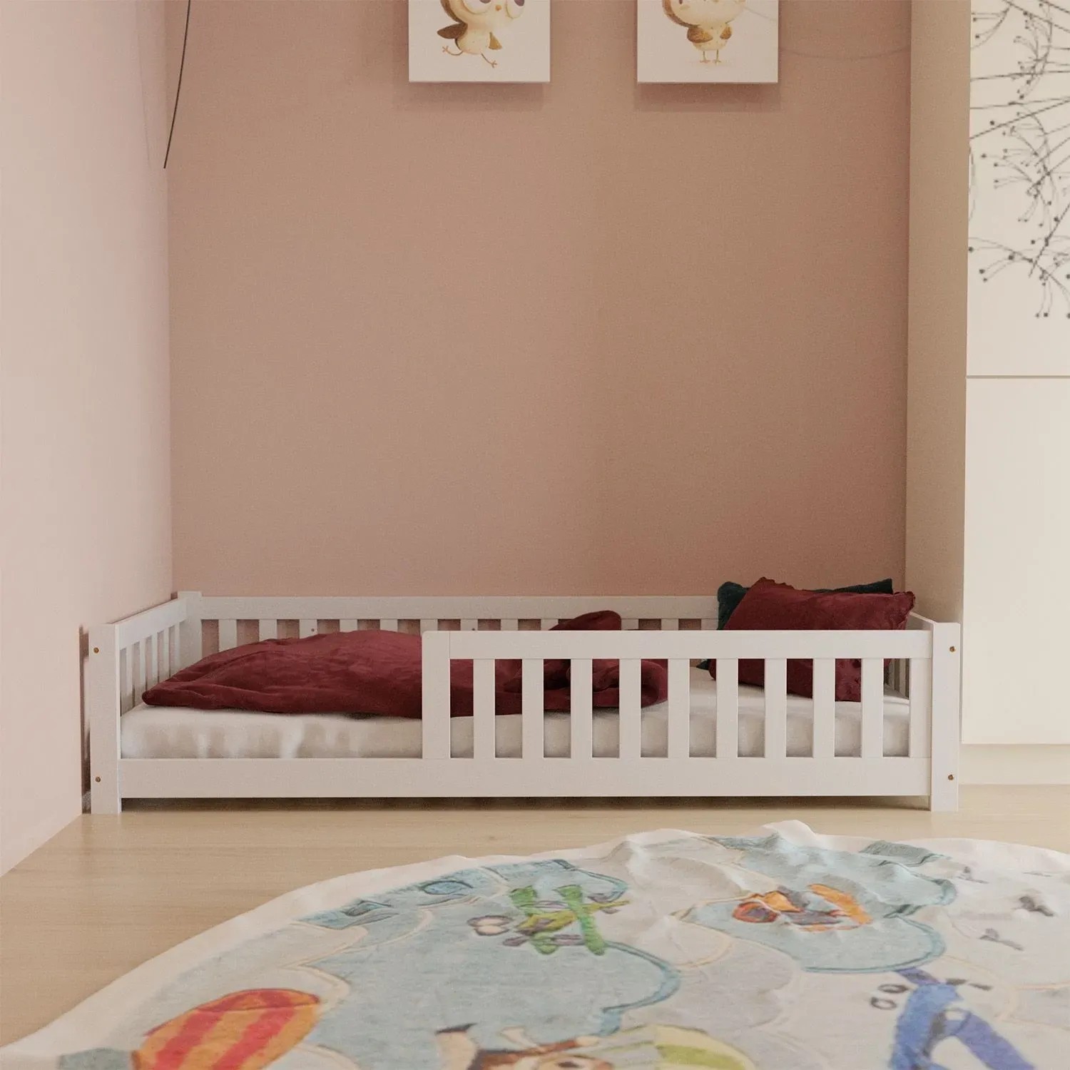 Weißes Juskys Kinderbett Naya 90x200 cm mit Rausfallschutz und Lattenrost im Kinderzimmer.