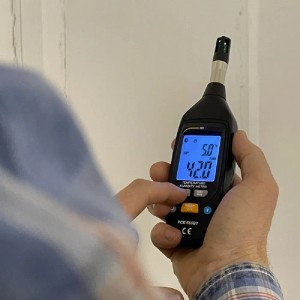 Hand hält PCE Instruments Feuchtemessgerät 555BT zur Messung von Temperatur und Luftfeuchtigkeit.