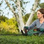 Frau schneidet Hecke mit Bosch Akku-Heckenschere Universal Hedge Cut 18-55. Kabellose Gartenschere im Einsatz.