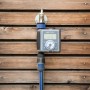 LUX Digitaler Bewässerungscomputer EBC-8/1 am Wasserhahn mit Schlauchanschluss vor Holzwand.