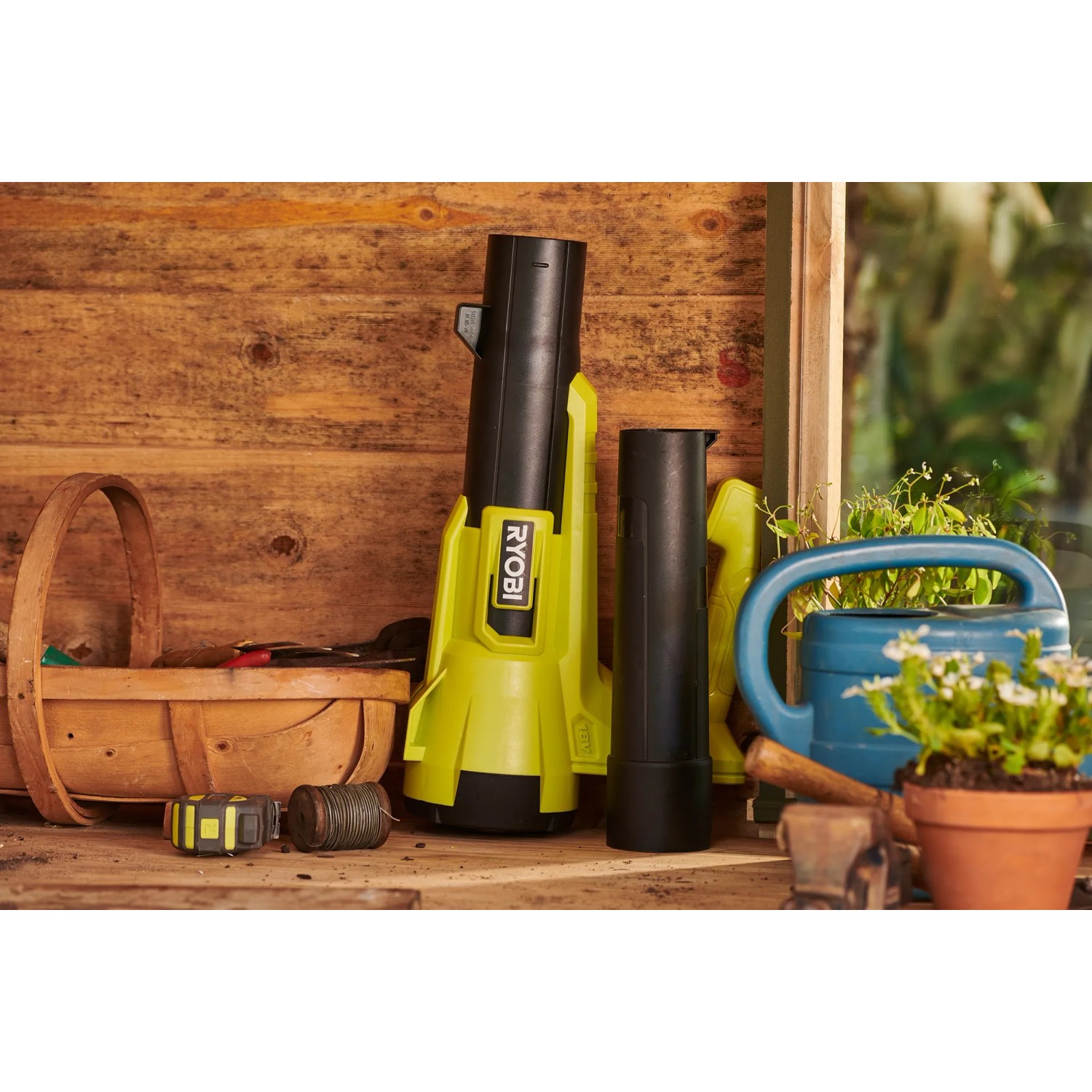 Ryobi Akku-Laubgebläse RY18BLA-140 One+ mit Akku und Ladegerät, stehend auf einer Werkbank.