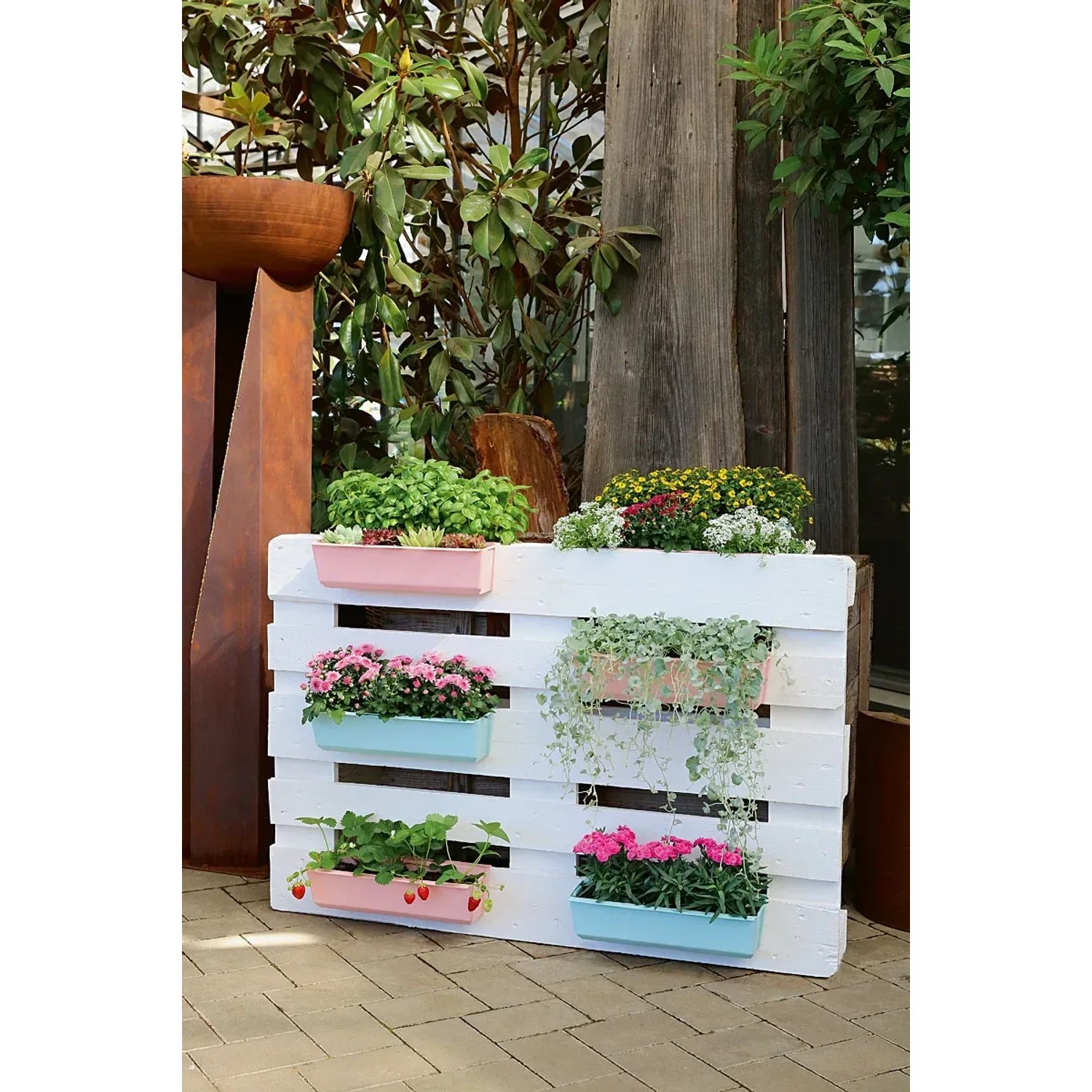 Europalette mit Geli Pflanzgefäßen in Zartrosa und Türkis, bepflanzt mit Blumen und Kräutern.
