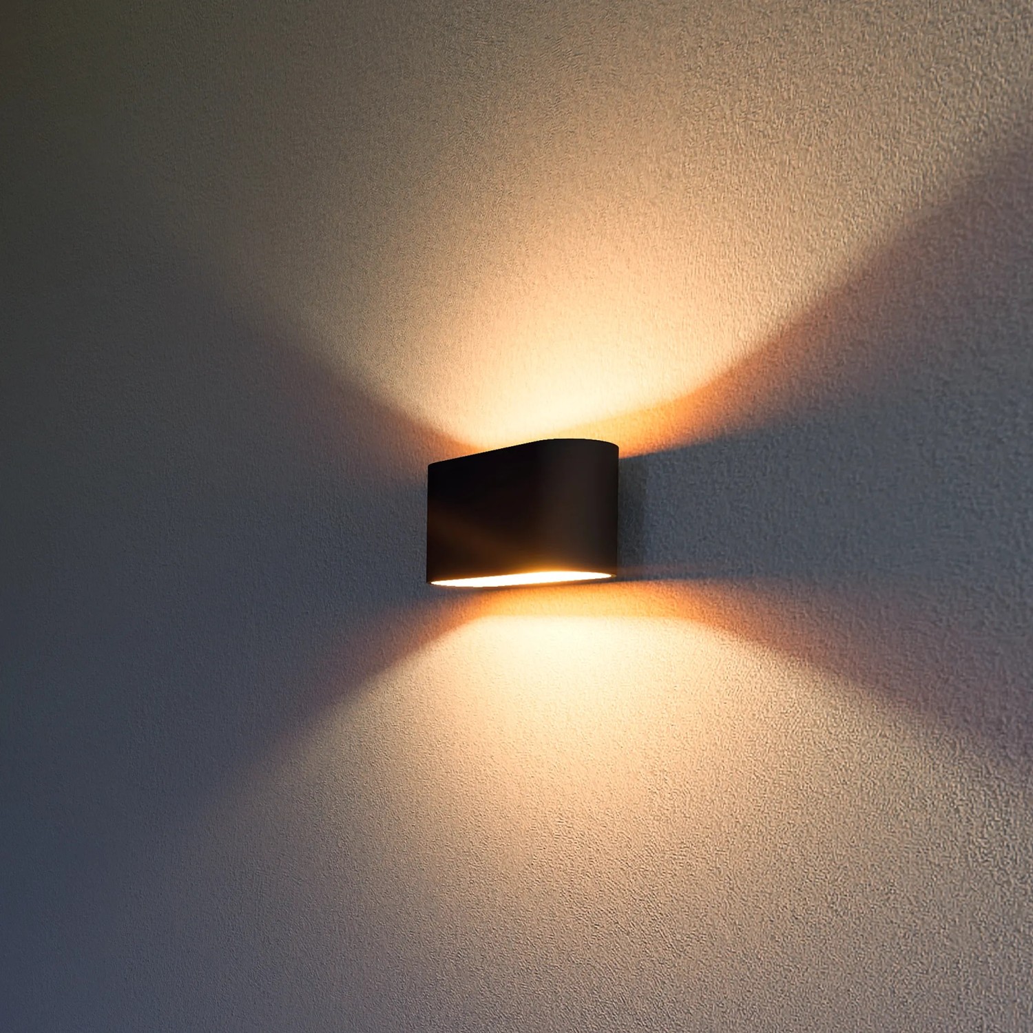 Rechteckige, schwarze Wandleuchte mit goldenem Reflektor, die warmes Licht nach oben und unten wirft.