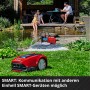 Einhell GE-AW 1144 SMART Hauswasserautomat im Garten mit Teich und Familie im Hintergrund.