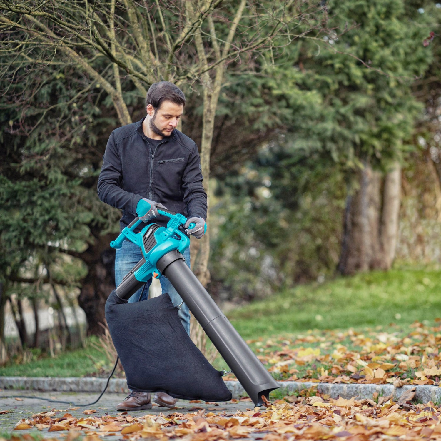 Mann benutzt Gardena Elektro-Laubbläser ErgoJet 3000 zum Laubsaugen im Garten.