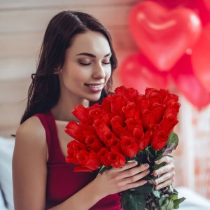Lachende Frau hält großen Strauß roter Kunstrosen aus Polyester. Perfekt als Dekoblumen für Romantik, Hochzeit, Valentinstag.