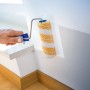 LUX Dispersionswalze 15 cm beim Streichen einer Wand. Farbwalze mit gelben Streifen und blauem Griff.