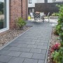 Diephaus Kantenstein Basalt mit Glimmer, eingefasster Gartenweg mit Sitzgruppe im Hintergrund.