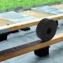 Schwarze Bauheld Terrassenpads Rolle aus Gummigranulat auf Holzbalken für Terrassenunterkonstruktion, Trittschalldämmung.