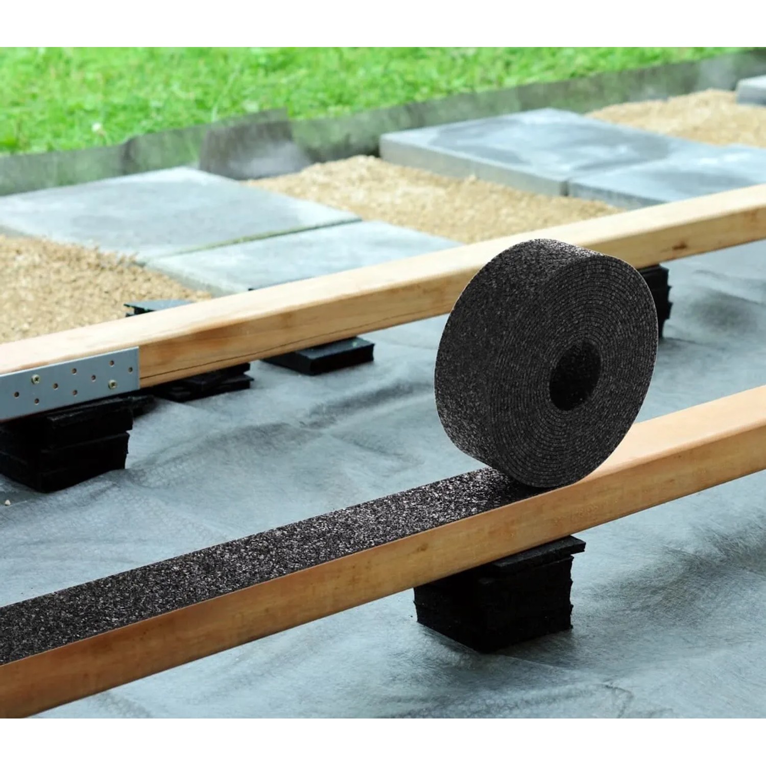 Schwarze Bauheld Terrassenpads Rolle aus Gummigranulat auf Holzbalken für Terrassenunterkonstruktion, Trittschalldämmung.