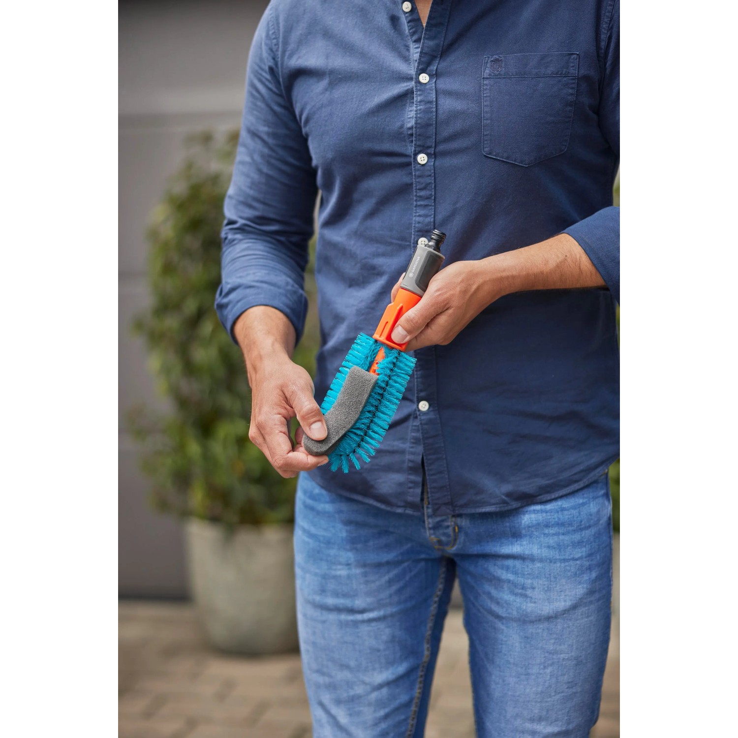 Gardena Cleansystem Fahrradbürste in Blau mit Borsten und Schwamm, gehalten von einer Person.