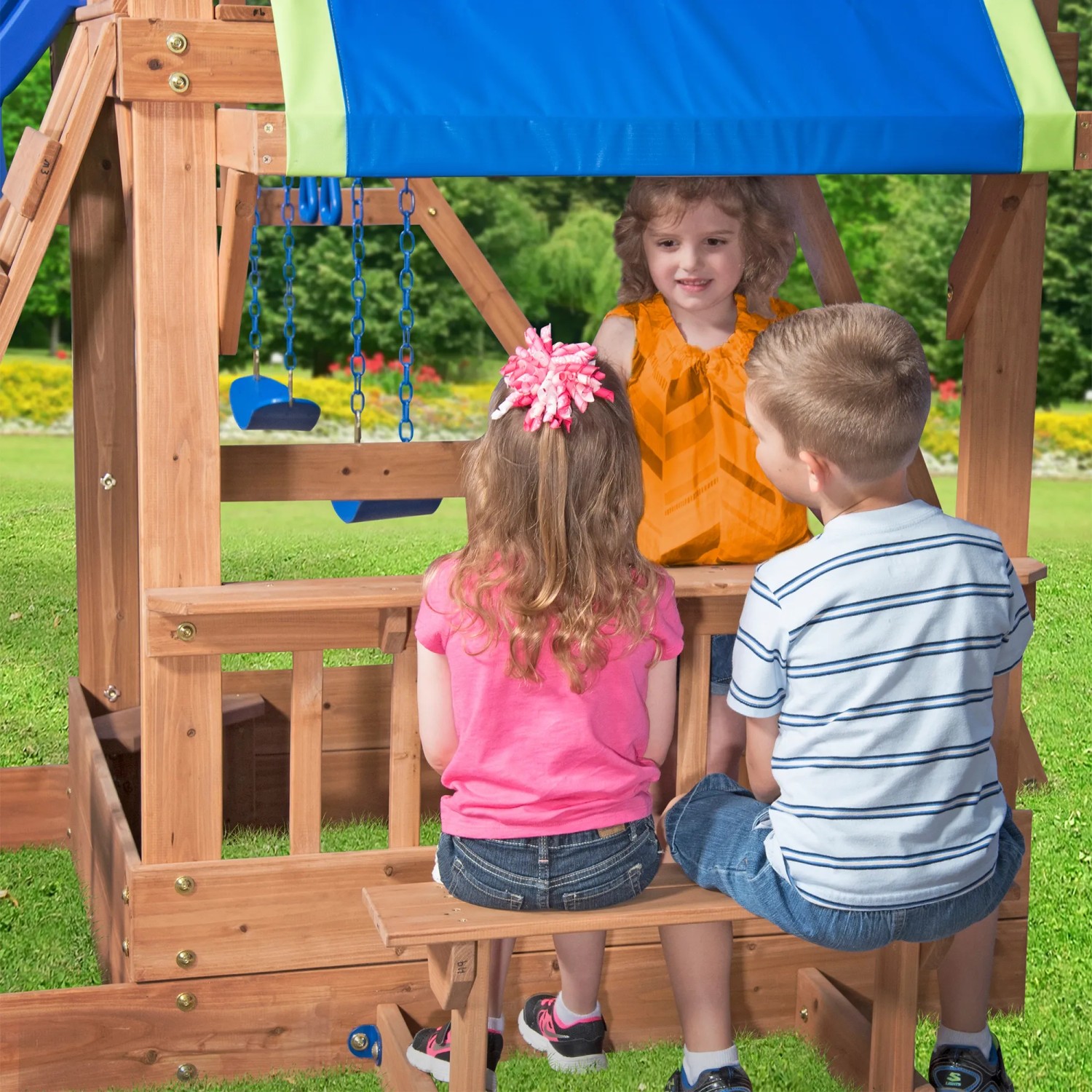 Kinder sitzen am Imbissbereich des Spielturms Northbrook aus Zedernholz mit Schaukel und Rutsche.