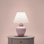 Rosa Vliestapete mit dezentem Art Deco Geometrie-Muster, an einer Wand hinter einer pinken Lampe.