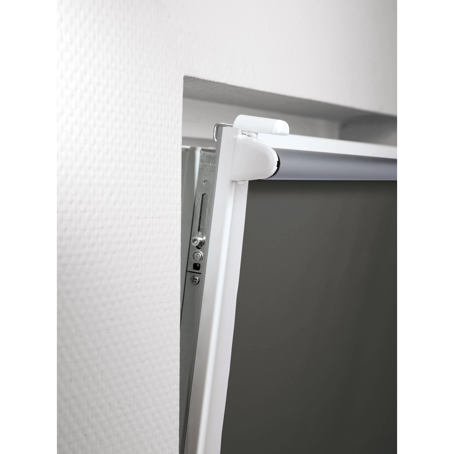 Detailaufnahme: Grau Thermo-Rollo Manresa mit Klemmträger am Fensterrahmen.