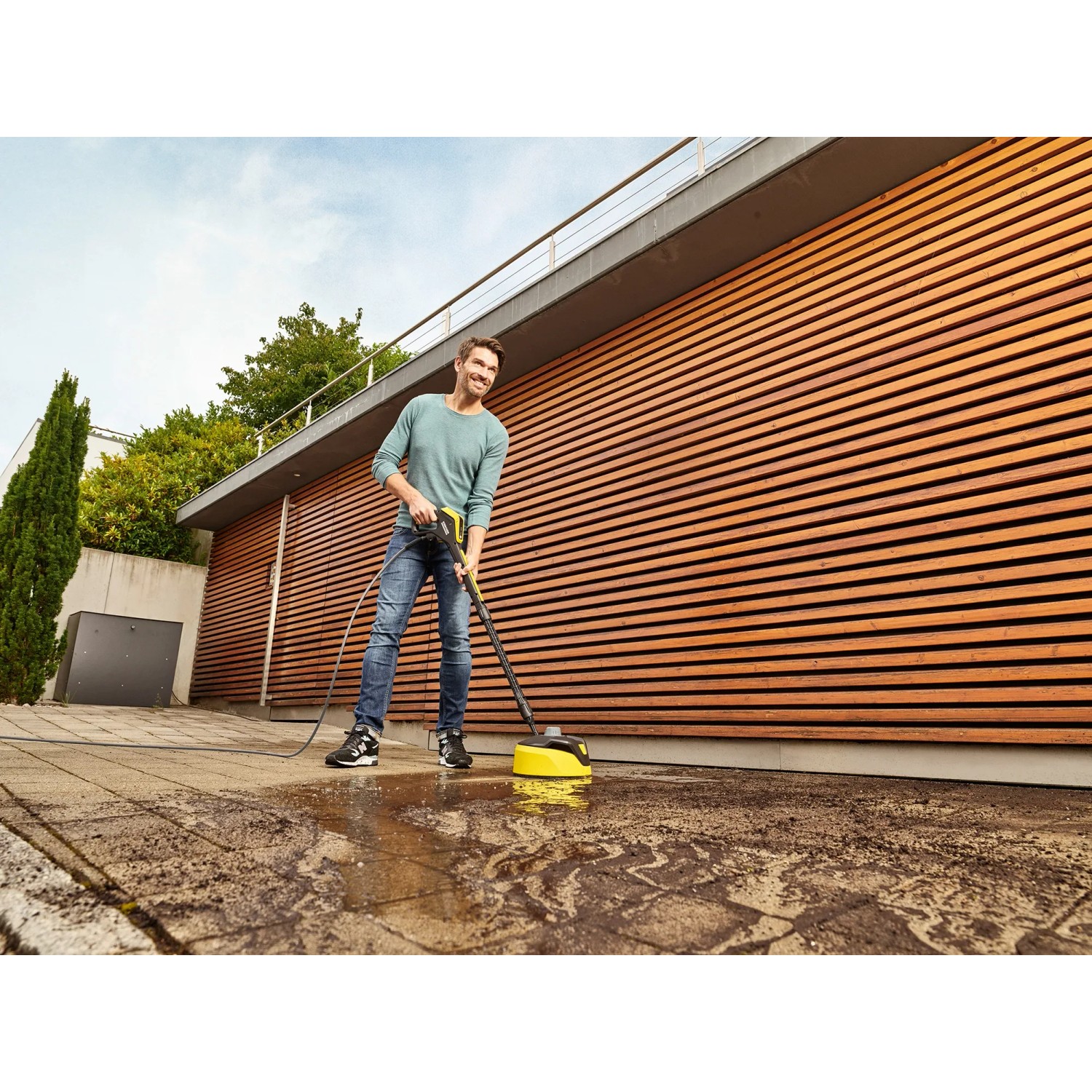 Mann reinigt Terrasse mit Kärcher Hochdruckreiniger K 5 Premium Smart Control Flex Home.