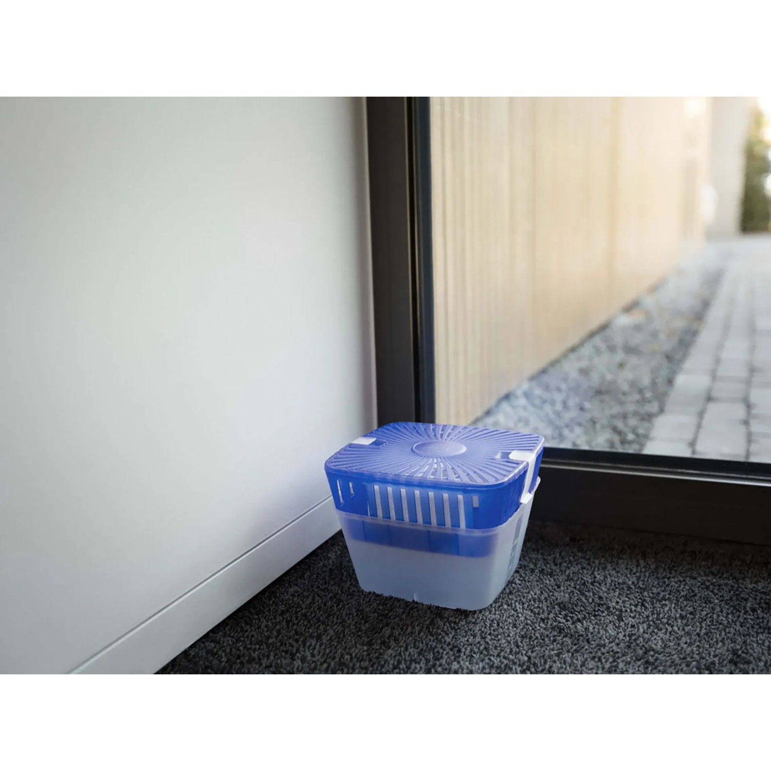UHU Luftentfeuchter Original 450g im Raum, blau-transparenter Behälter.