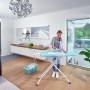 Frau bügelt Wäsche auf dem Leifheit AirBoard Compact M Plus Bügeltisch mit Bügeleisen.
