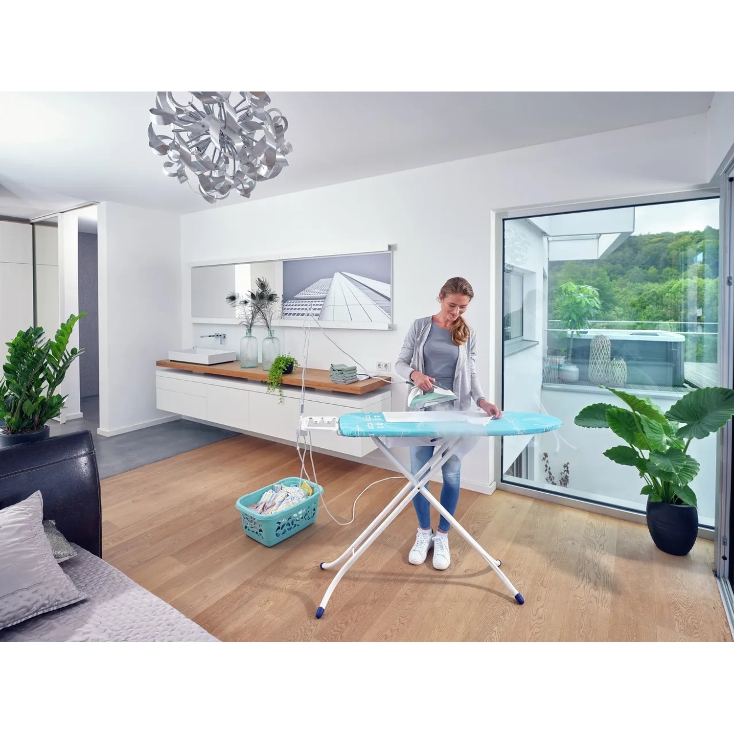 Frau bügelt Wäsche auf dem Leifheit AirBoard Compact M Plus Bügeltisch mit Bügeleisen.