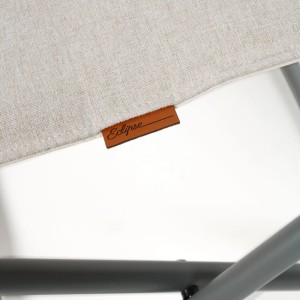 Detailaufnahme: Beige Eclipse Campinghocker mit Logo-Etikett und Metallgestell.