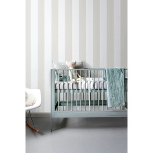 Gestreifte Tapete in Beige und Weiß an einer Wand im Kinderzimmer mit Babybett. Dekorative Wandgestaltung.