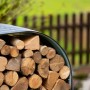 Anthrazitfarbenes Westmann Kaminholzregal aus Stahl, gefüllt mit Holzscheiten.