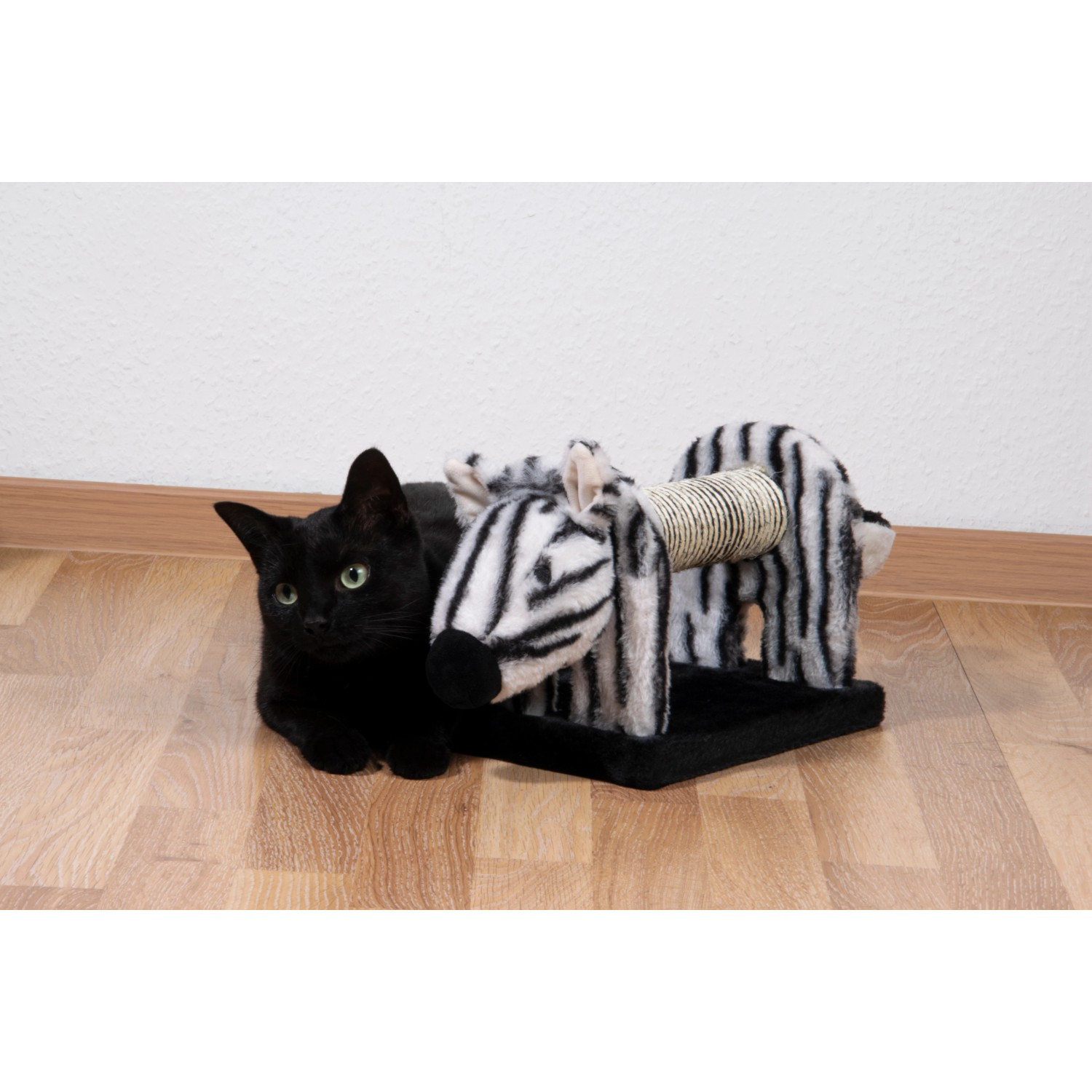Schwarze Katze liegt vor Dobar Kratztier Zebra. Katzenbürste mit Sisal-Kratzrolle.