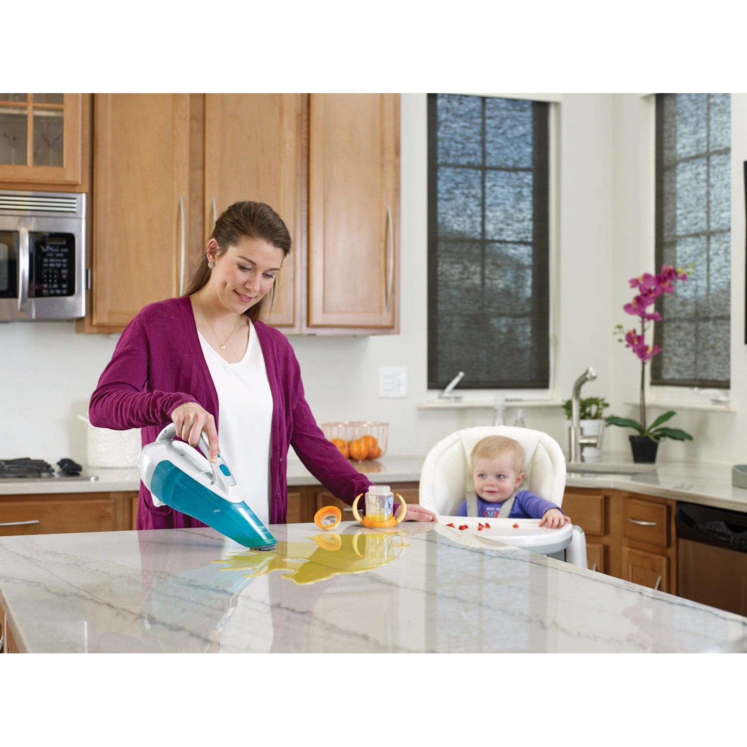 Frau saugt Flüssigkeit mit Black+Decker Akku-Handstaubsauger Dustbuster auf Küchentisch.
