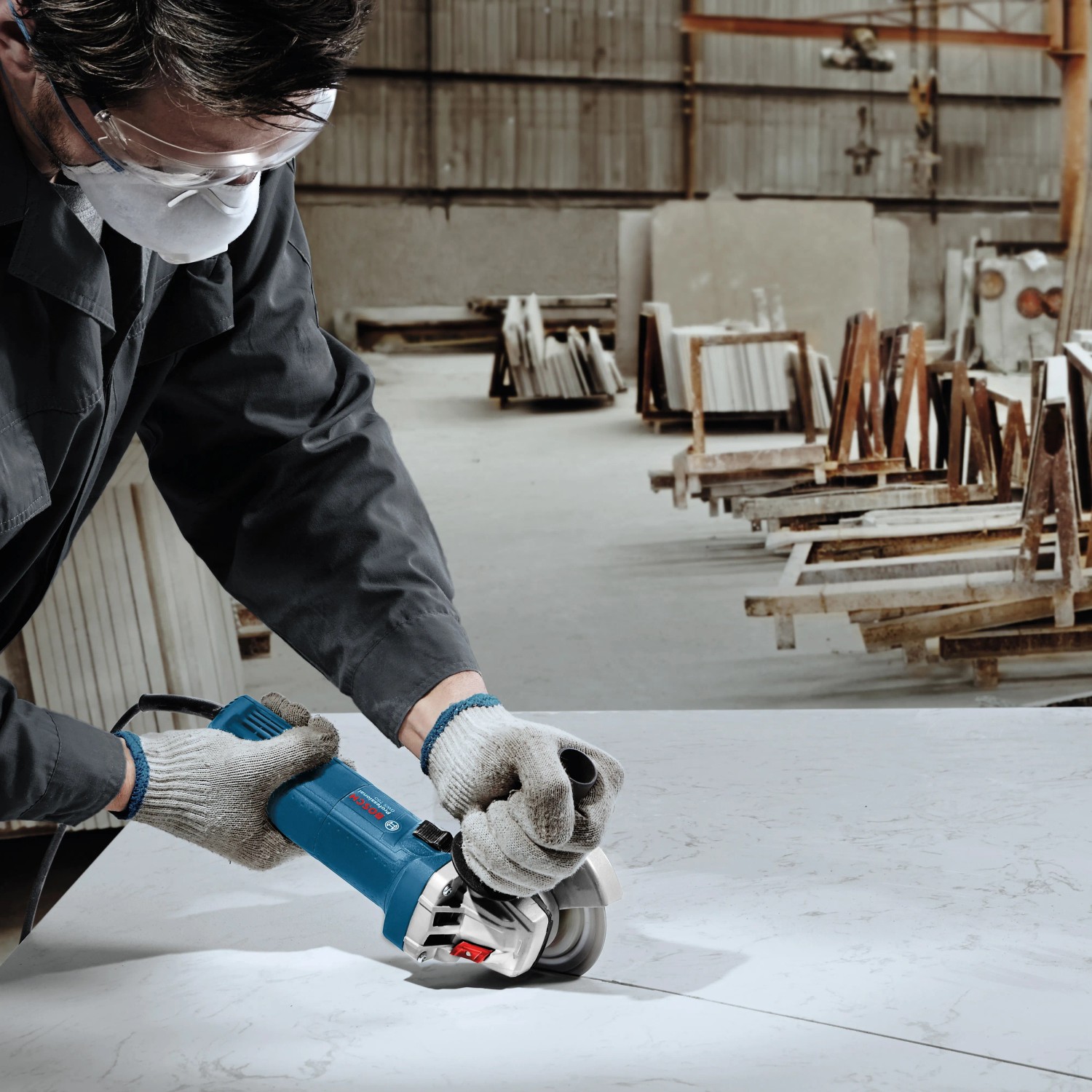 Handwerker beim Schneiden einer Platte mit dem blauen Bosch Professional Winkelschleifer GWS 750-125.