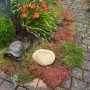 Kobolo Dekostein DRAGONFLY aus Naturstein im Garten, neben einer Deko-Schildkröte.