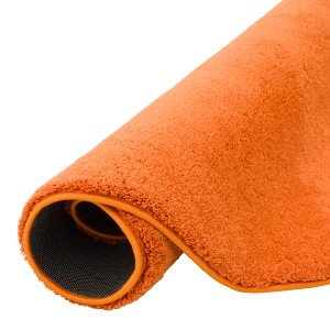 Gerollter, runder, orangefarbener Hochflor Teppich (160x160cm) der Marke Pergamon, super soft.