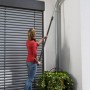 Frau nutzt Gardena combisystem Winkelbesen mit Stiel zur Reinigung einer Dachrinne.