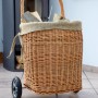 Kaminholzwagen aus Weide mit Rädern, gefüllt mit Holz, vor Kaminofen. Zubehör für Kamine.