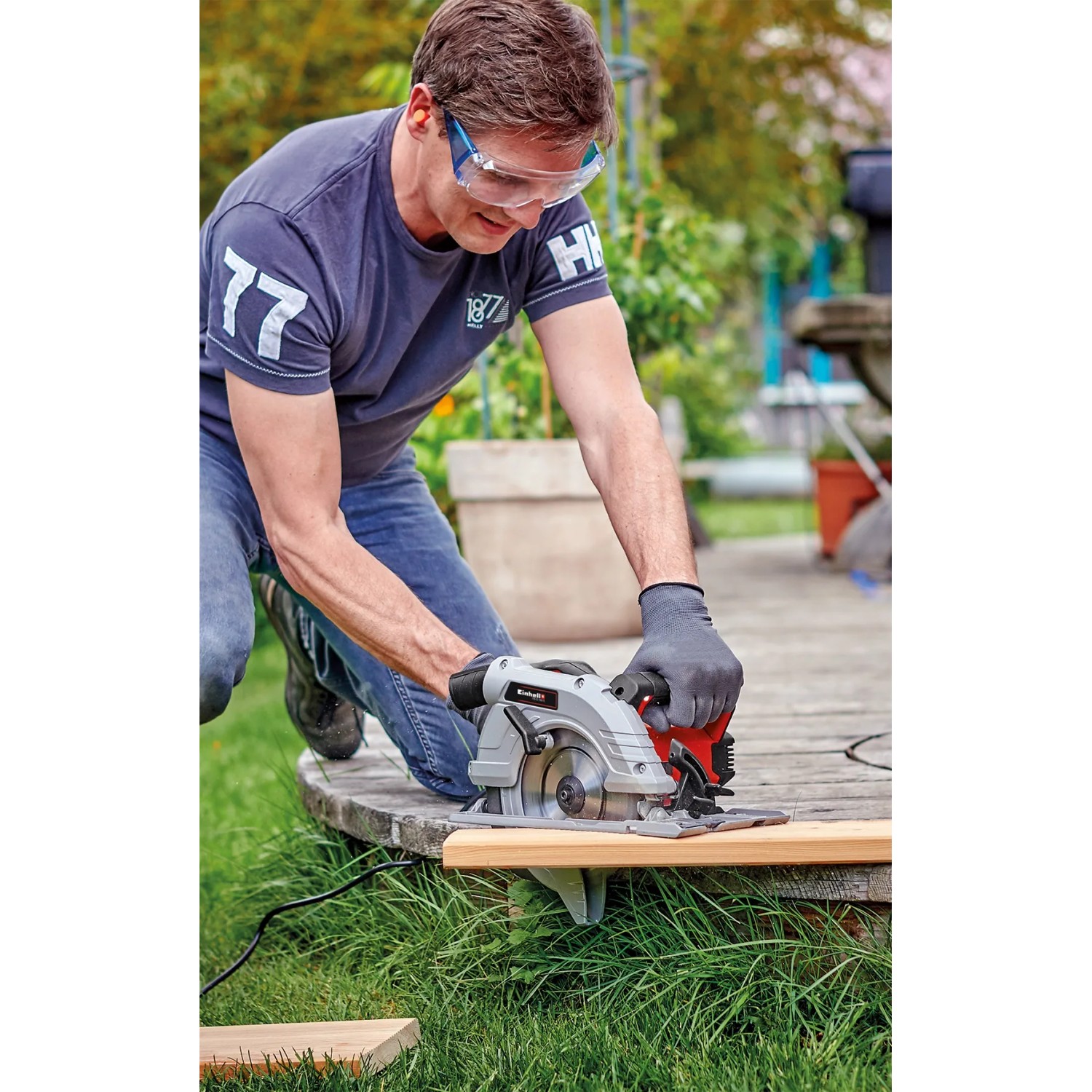 Mann sägt Holz mit Einhell Handkreissäge TE-CS 190/1 im Garten.