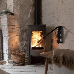 Wandmontierter, schwarzer ECD Germany Holzspalter aus Gusseisen mit Holzgriff neben Kamin.