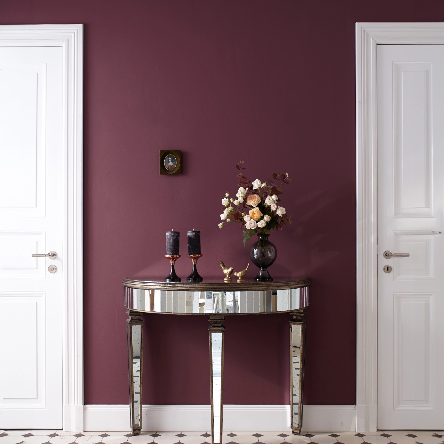 Wand in Purpur mit Alpina Feine Farben No. 17 Farbe der Könige®, Konsole mit Deko, weiße Tür im Hintergrund.