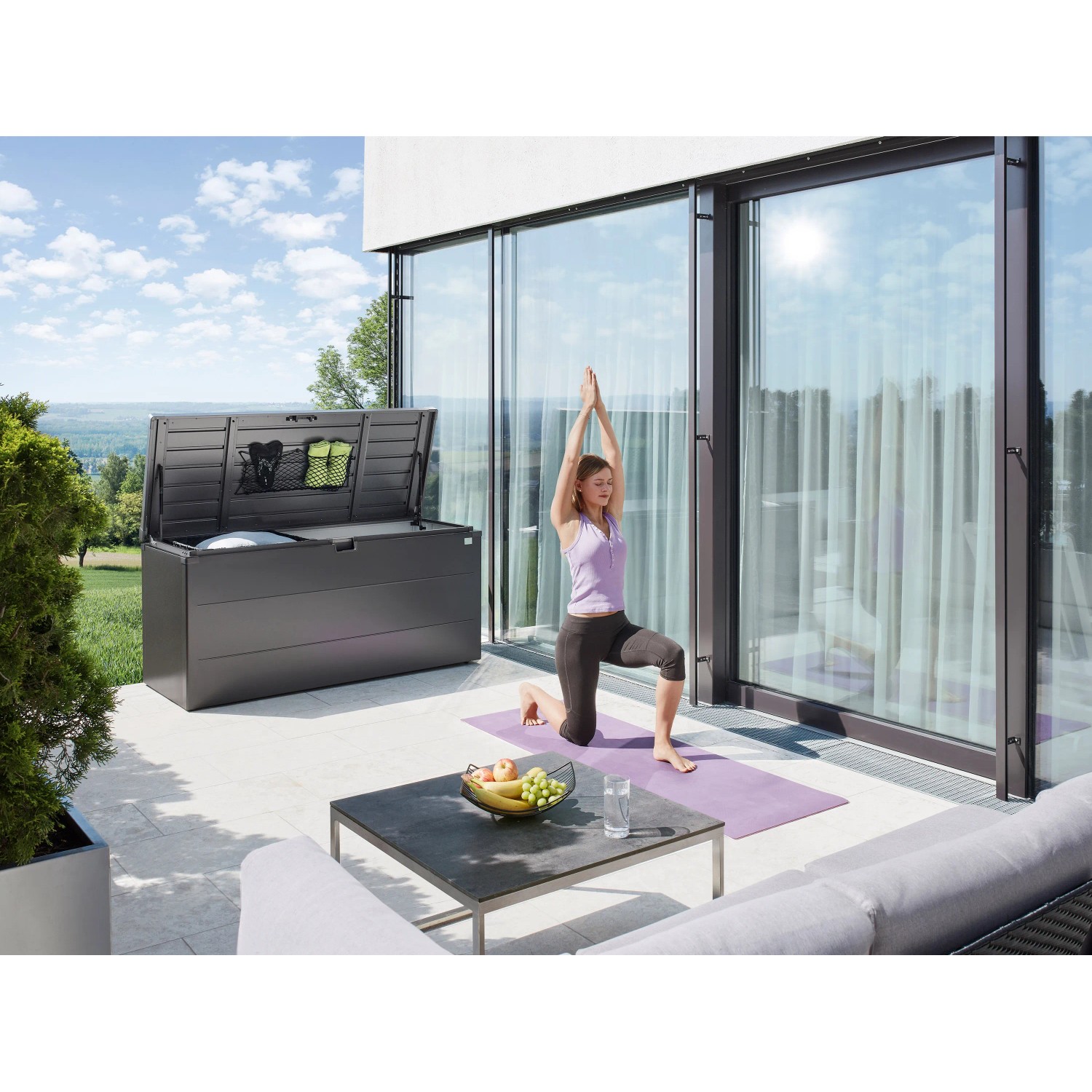 Biohort Stylebox 140, dunkelgrau-metallic, mit geöffnetem Deckel und Yoga-Szene auf Terrasse.