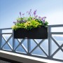Graphitschwarzer Lechuza Balconera Cottage 80 Blumenkasten mit Bepflanzung auf einem Balkon.