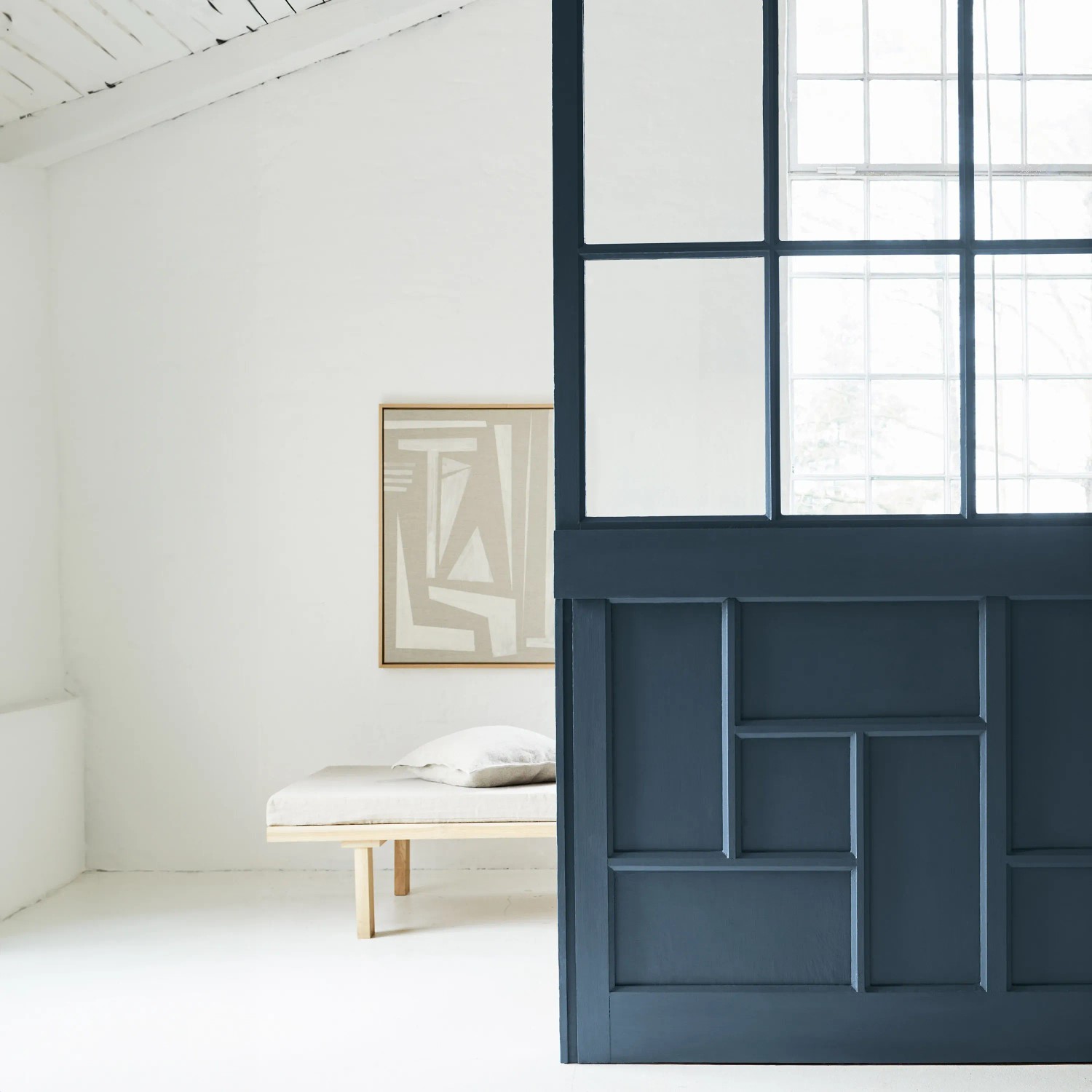 Alpina Buntlack „Himmlische Nachtmusik“: Blau lackierte Wand mit Fenster und Sitzbank im Raum.