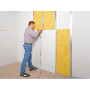 Mann montiert Dachausbau-Komplettpaket WLG 035 mit Mineralfaser Dämmstoffen an einer Wand.