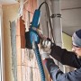 Bosch Professional GDE125EA-T Absaughaube für Winkelschleifer im Einsatz an einer Ziegelwand.